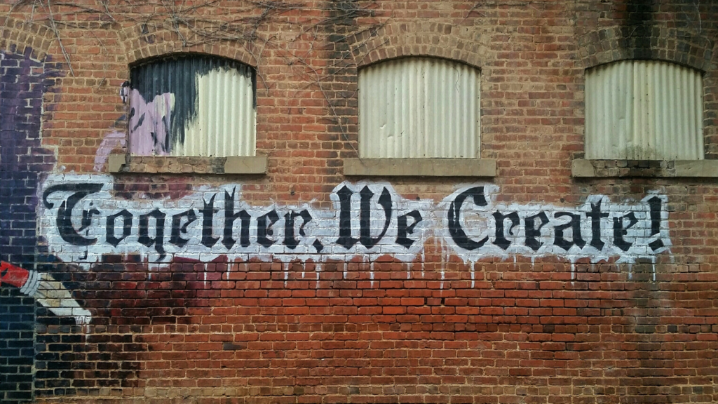 Graffiti on a brick wall that says "together we create"